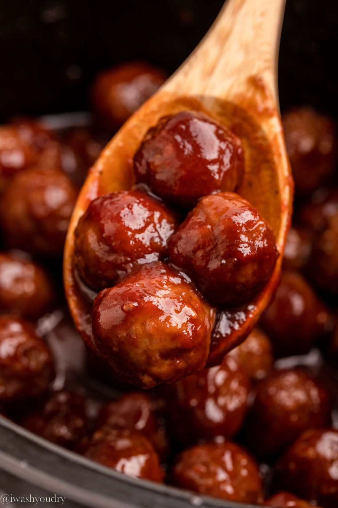 4 cookied meatballs on a wooden spoon. 