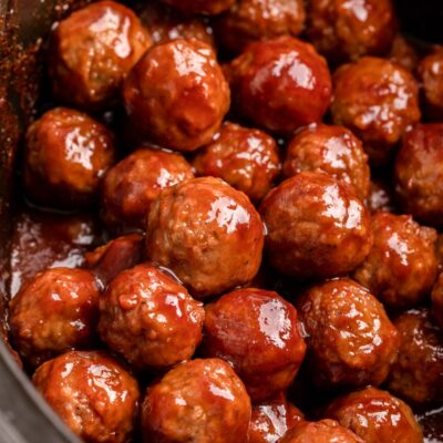 Cooked 3 ingredient cocktail meatballs in black slow cooker.