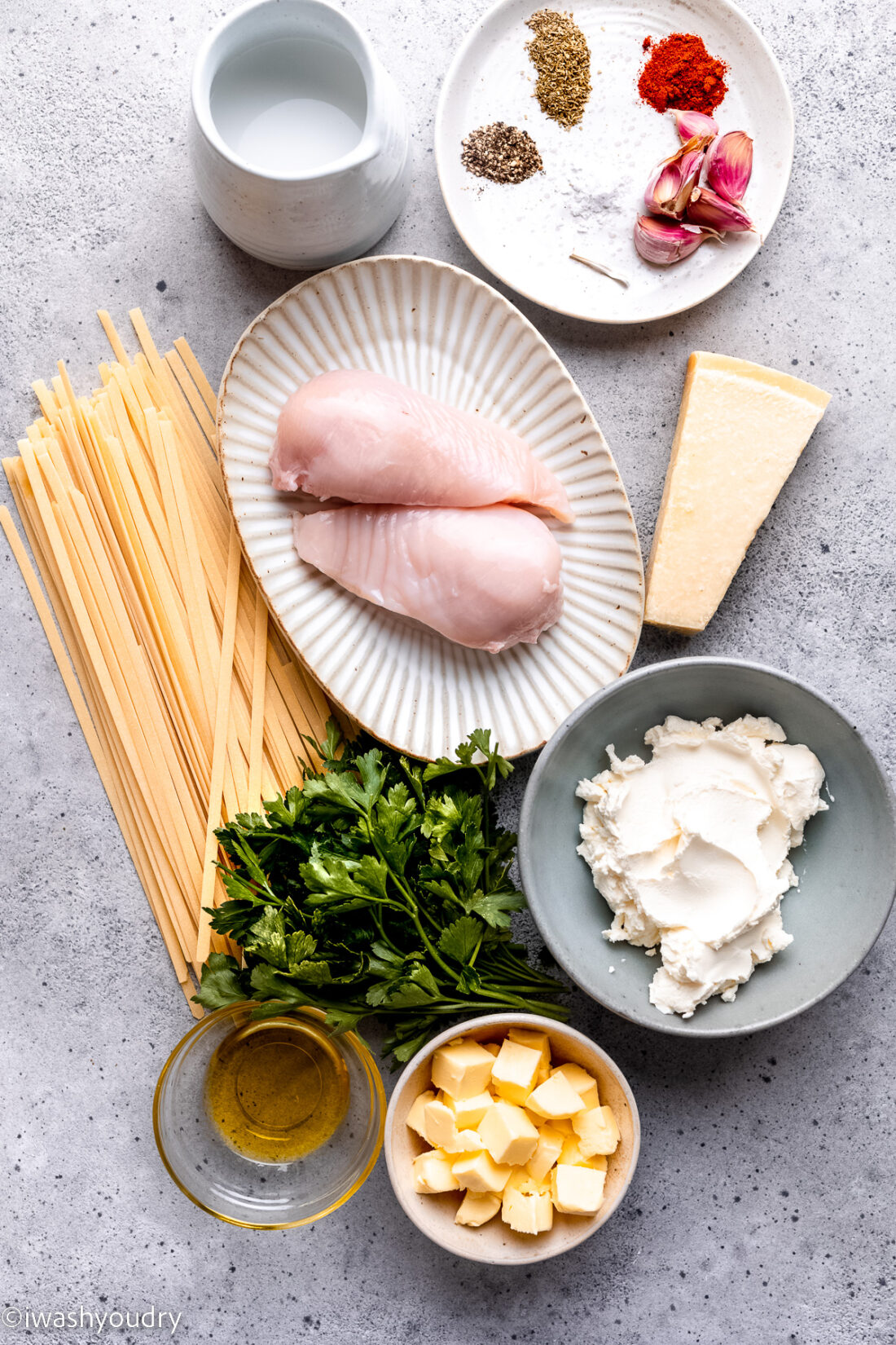 Ingredients for Chicken Alfredo on concrete countertop.