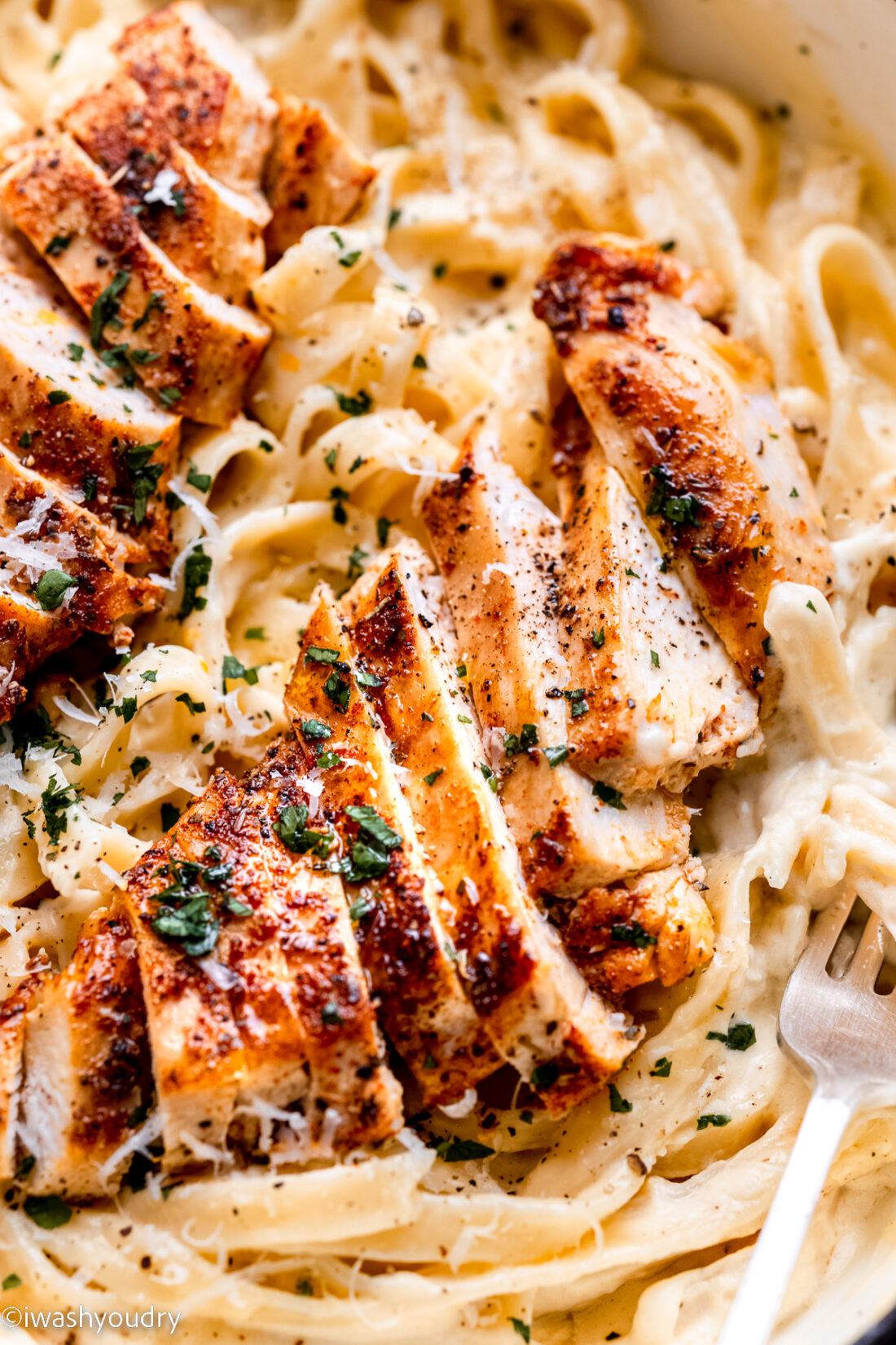 Sliced chicken on cooked fettuccine noodles. 