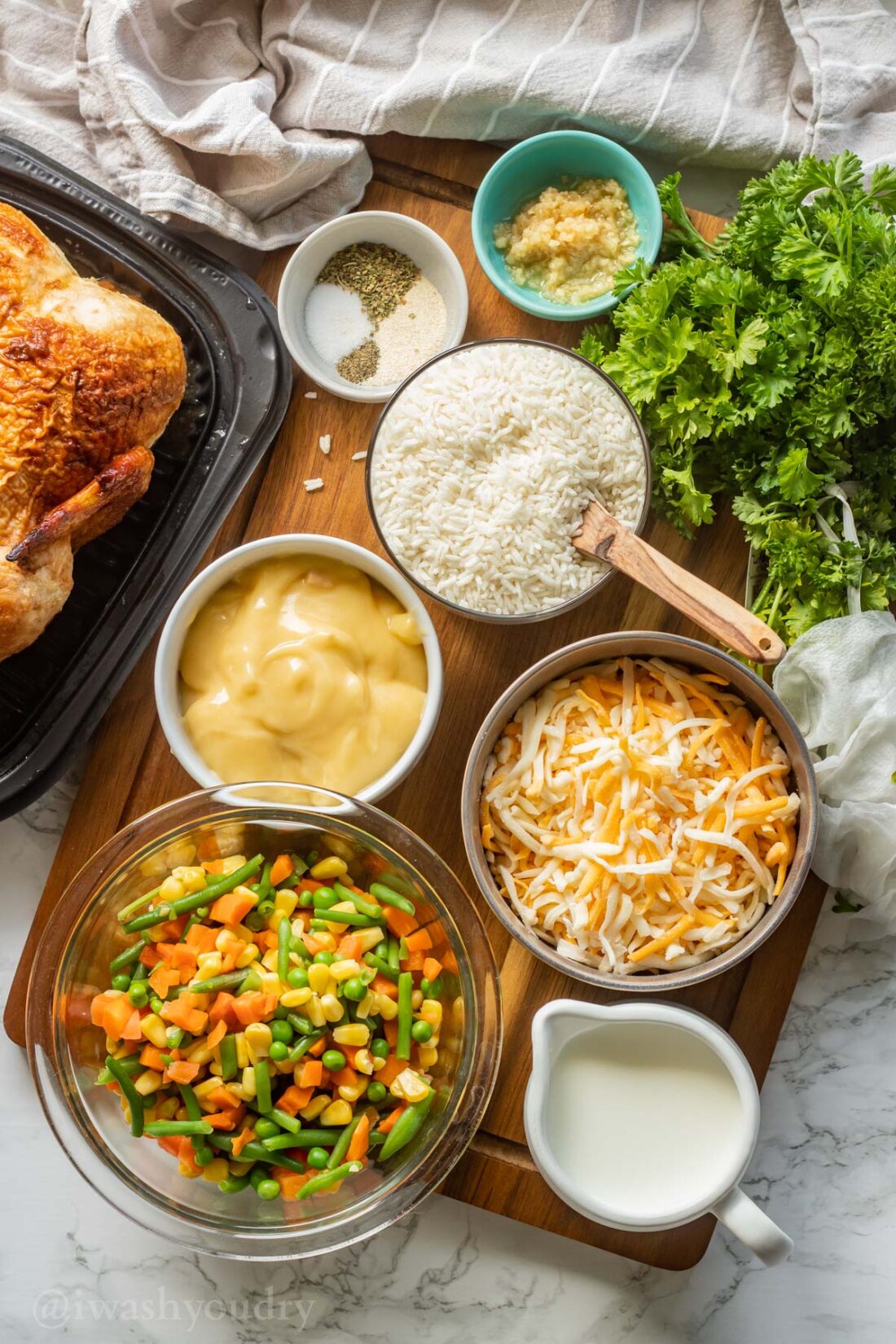 Ingredients for chicken and rice casserole on wood cutting board. 