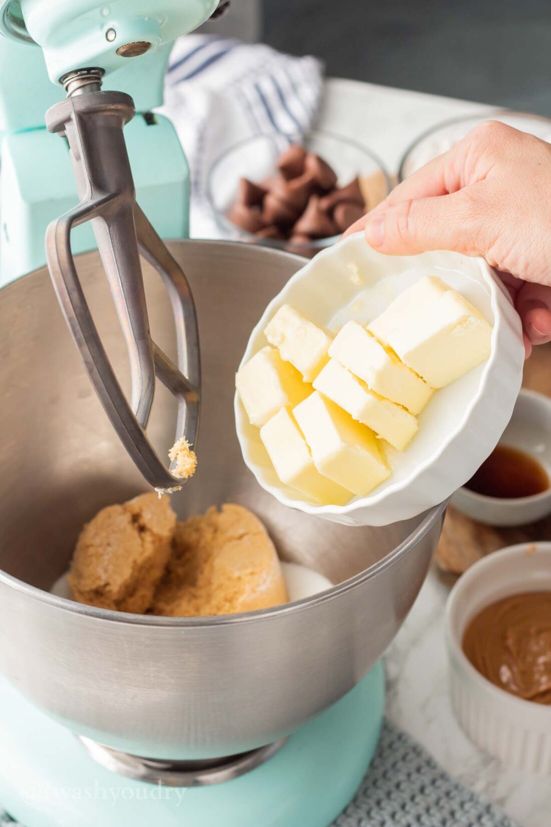 Butter in white dish above metal mixing bowl.