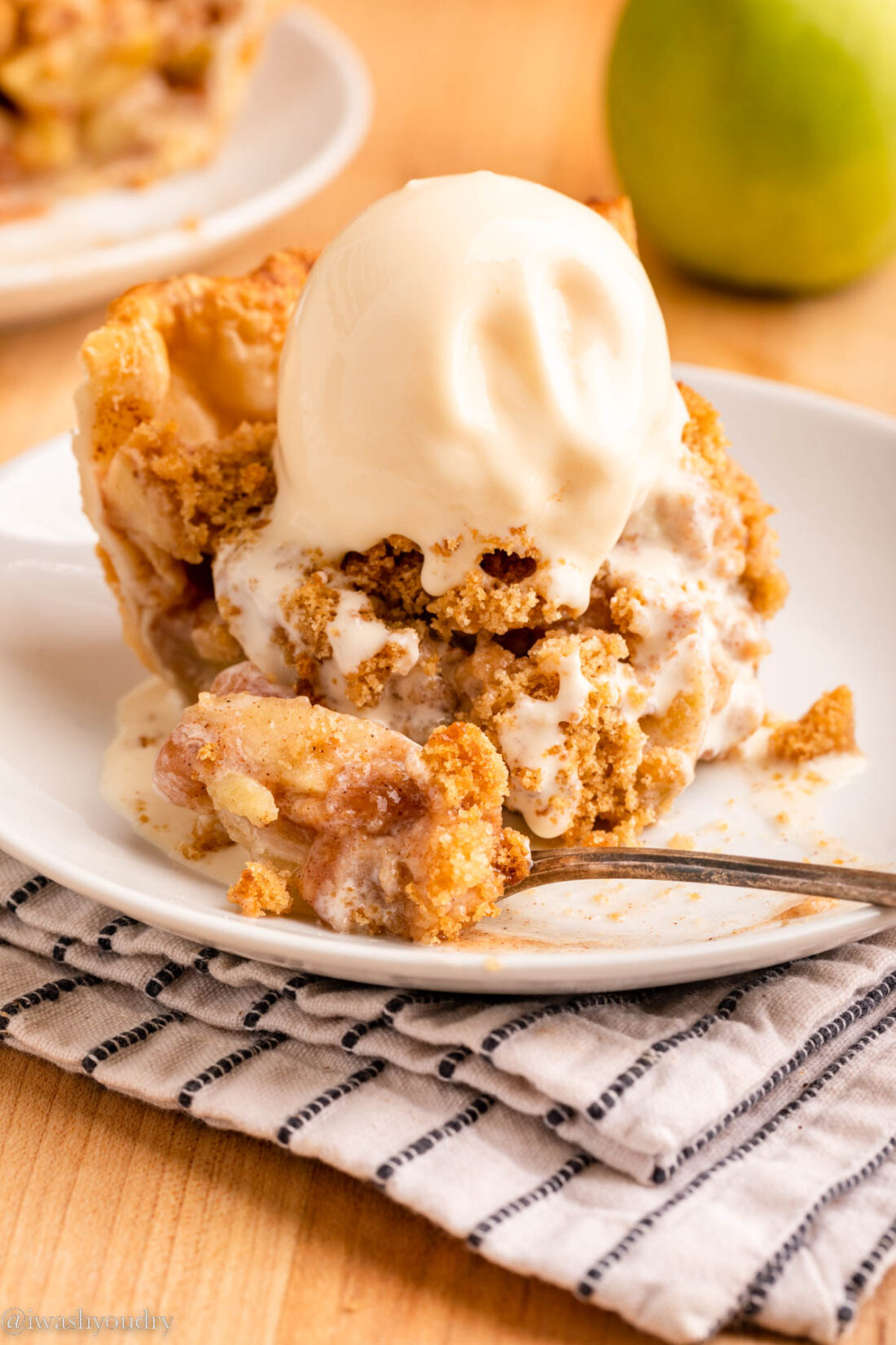 Slice of baked dutch apple pie on white plate with fork. 