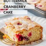 Slice of buttermilk cranberry cake on white plate with gold fork.