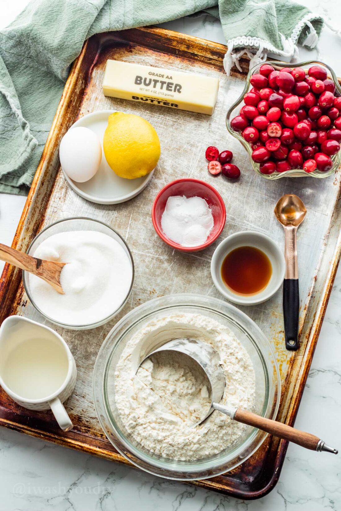 Ingredients for Buttermilk Cranberry Cake in glass bowls on a metal baking pan with green dish towel. 