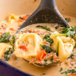 spoonful of tortellini soup with spinach and peppers.