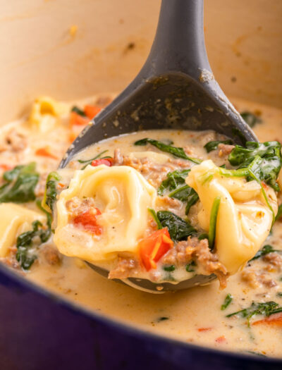 spoonful of tortellini soup with spinach and peppers.