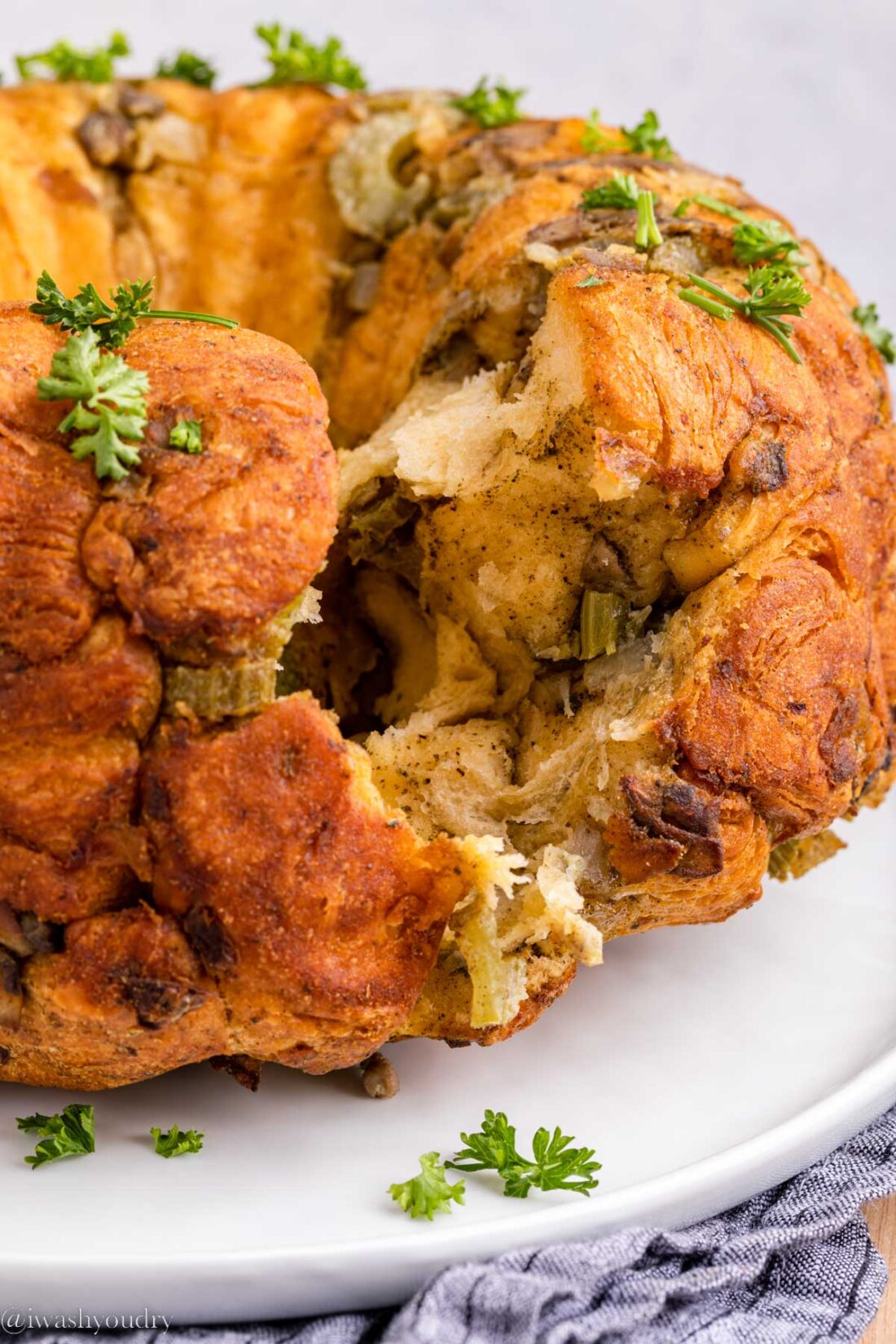 Baked stuffing ring with piece removed on white platter. 