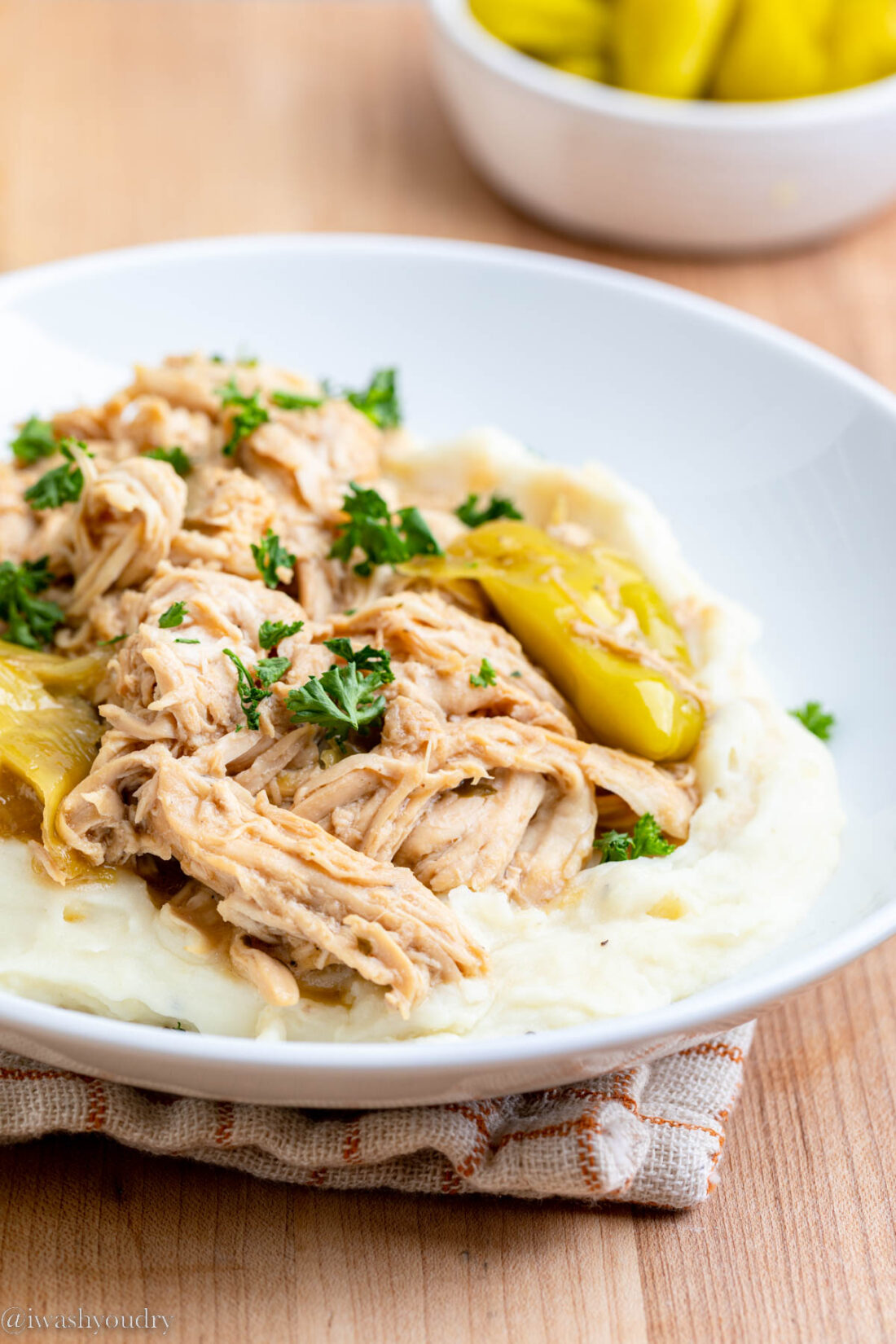 Cookied Slow Cooker Mississippi Chicken on mashed potatoes on white plate. 