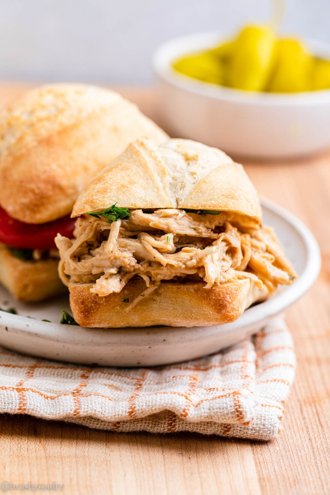 Cooked mississippi chicken on roll on white plate. 