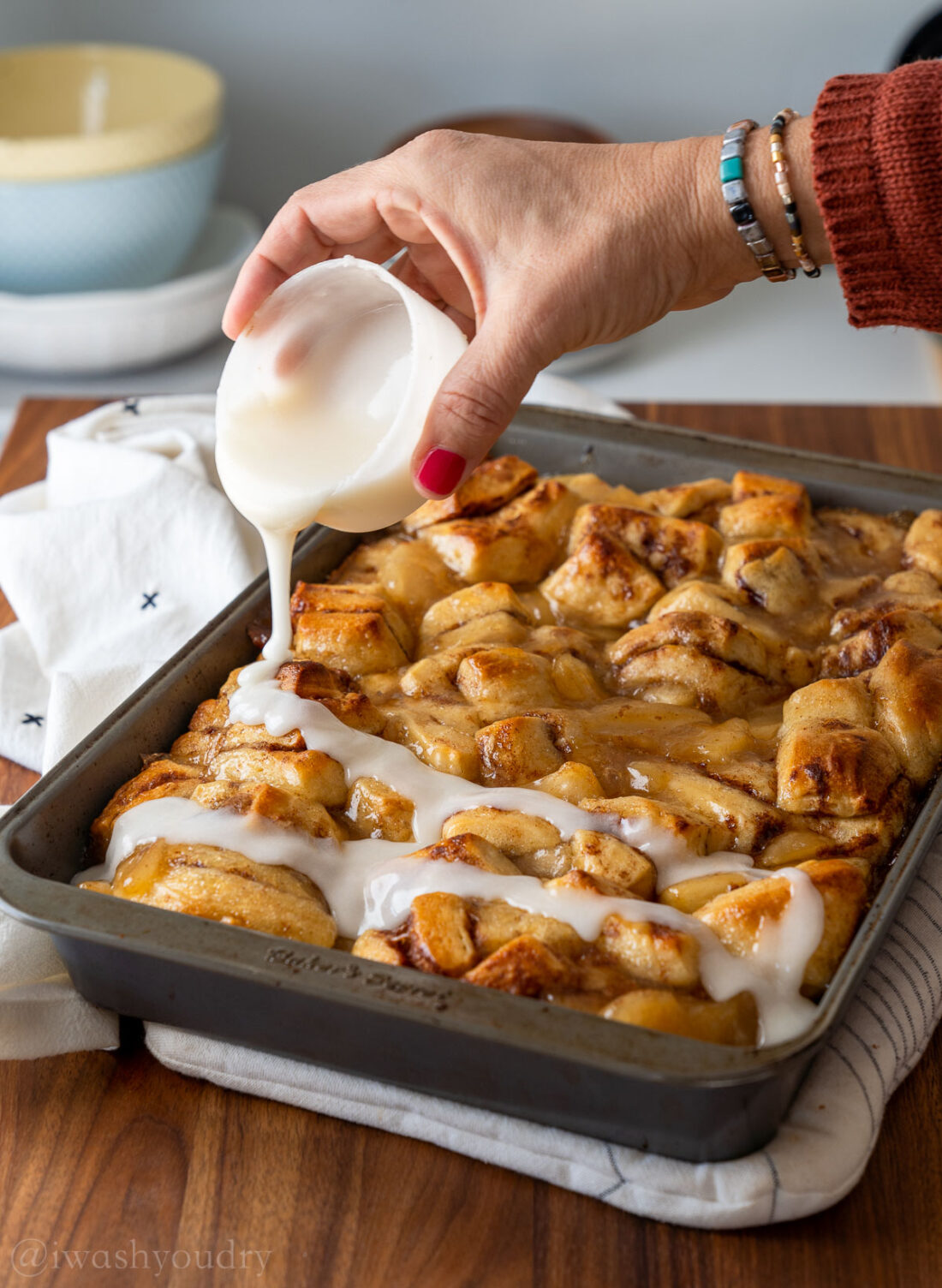 drizzling cinnamon rolls with icing.