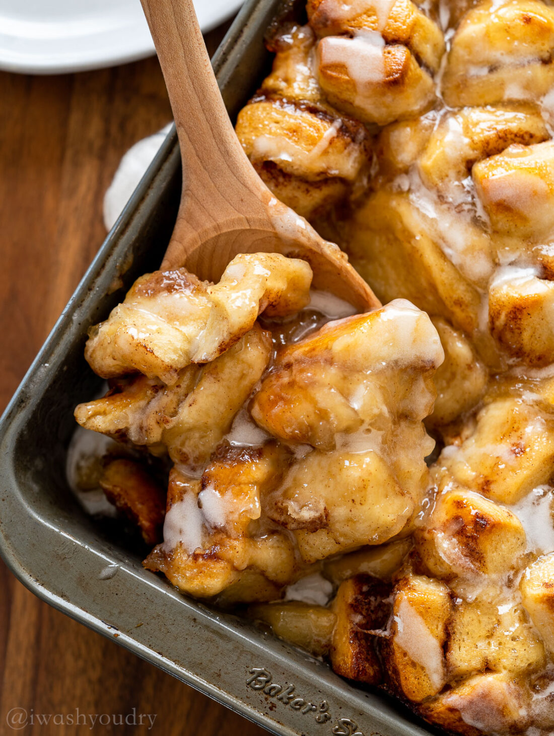 scoop of cinnamon roll bake with wooden spoon.