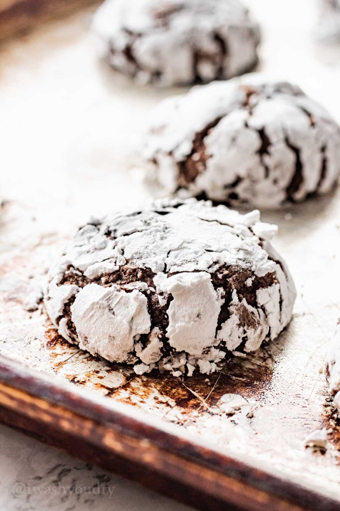 Baked chocolate crinkle cookies on metal pan. 