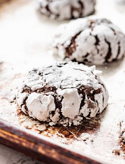 Baked chocolate crinkle cookies on metal pan.