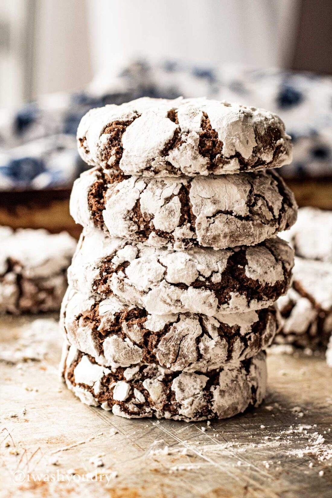 Baked chocolate crinkle cookies in a stack on metal pan. 