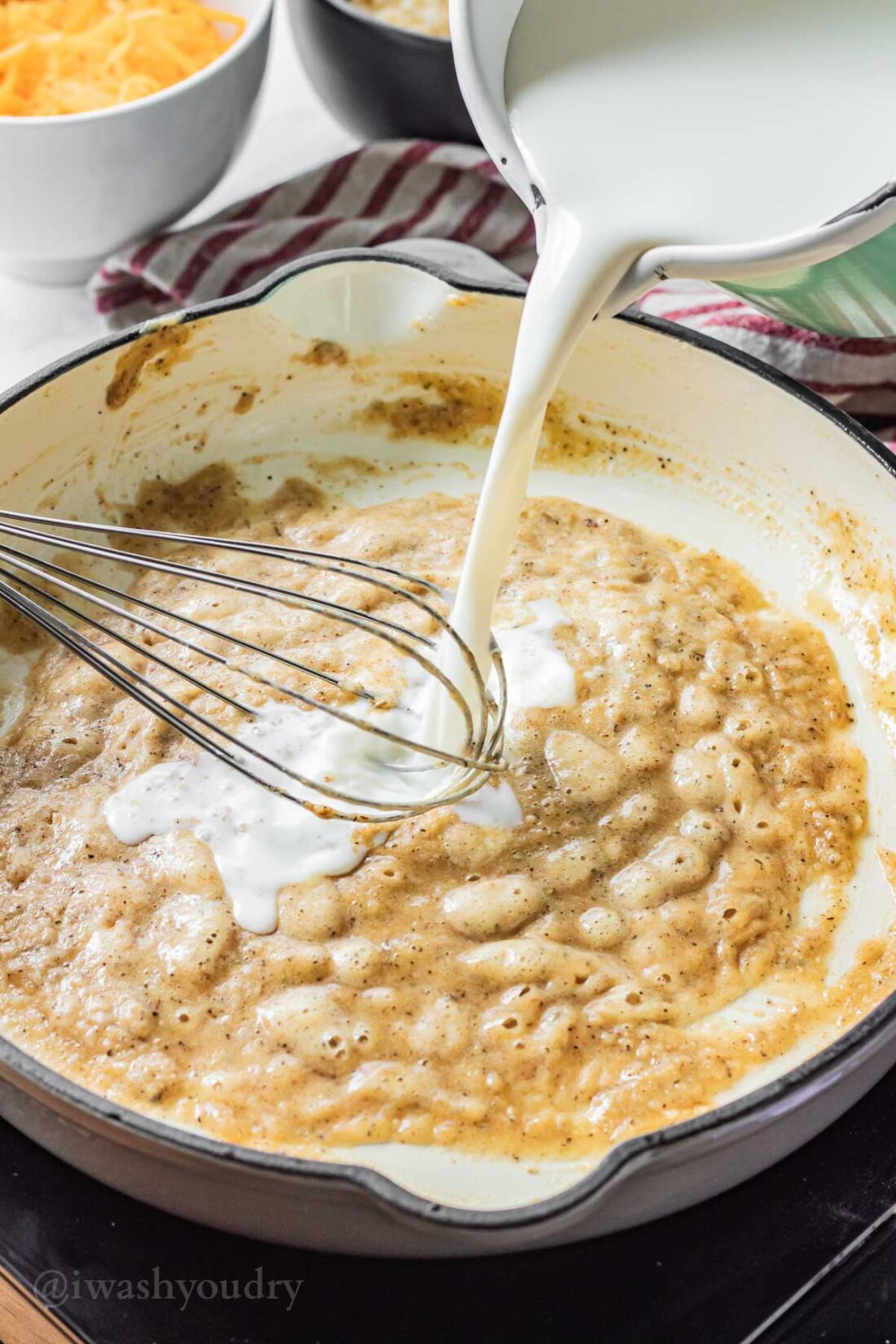 Pouring milk into cooked butter and flour. 