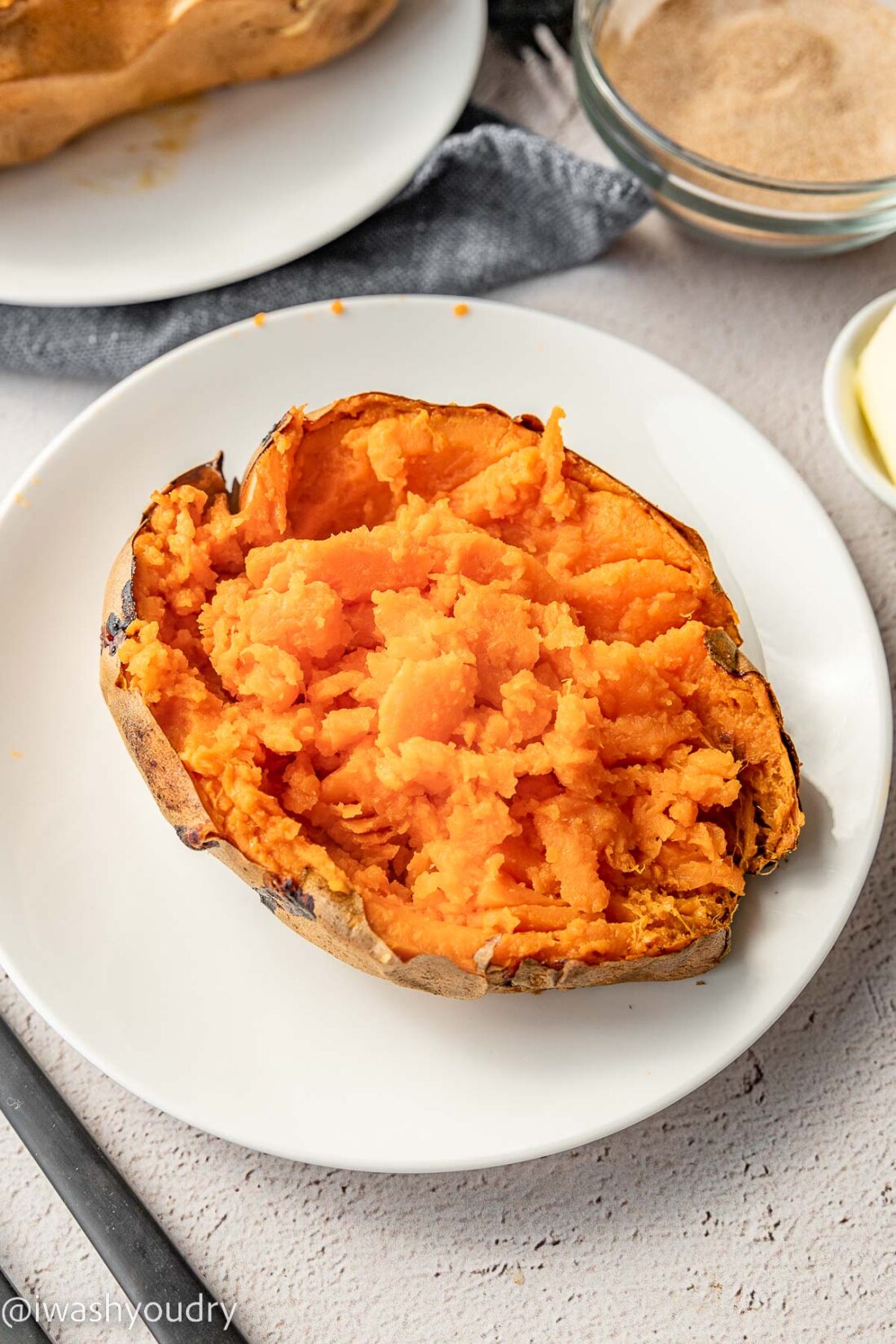 Cooked sliced open sweet potato on a white plate. 