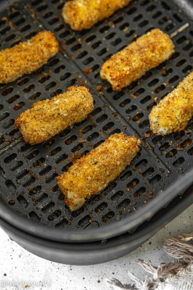 golden brown cheese sticks in air fryer basket.