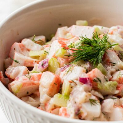 white bowl with creamy crab salad topped with fresh dill weed.