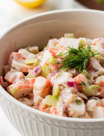 white bowl with creamy crab salad topped with fresh dill weed.