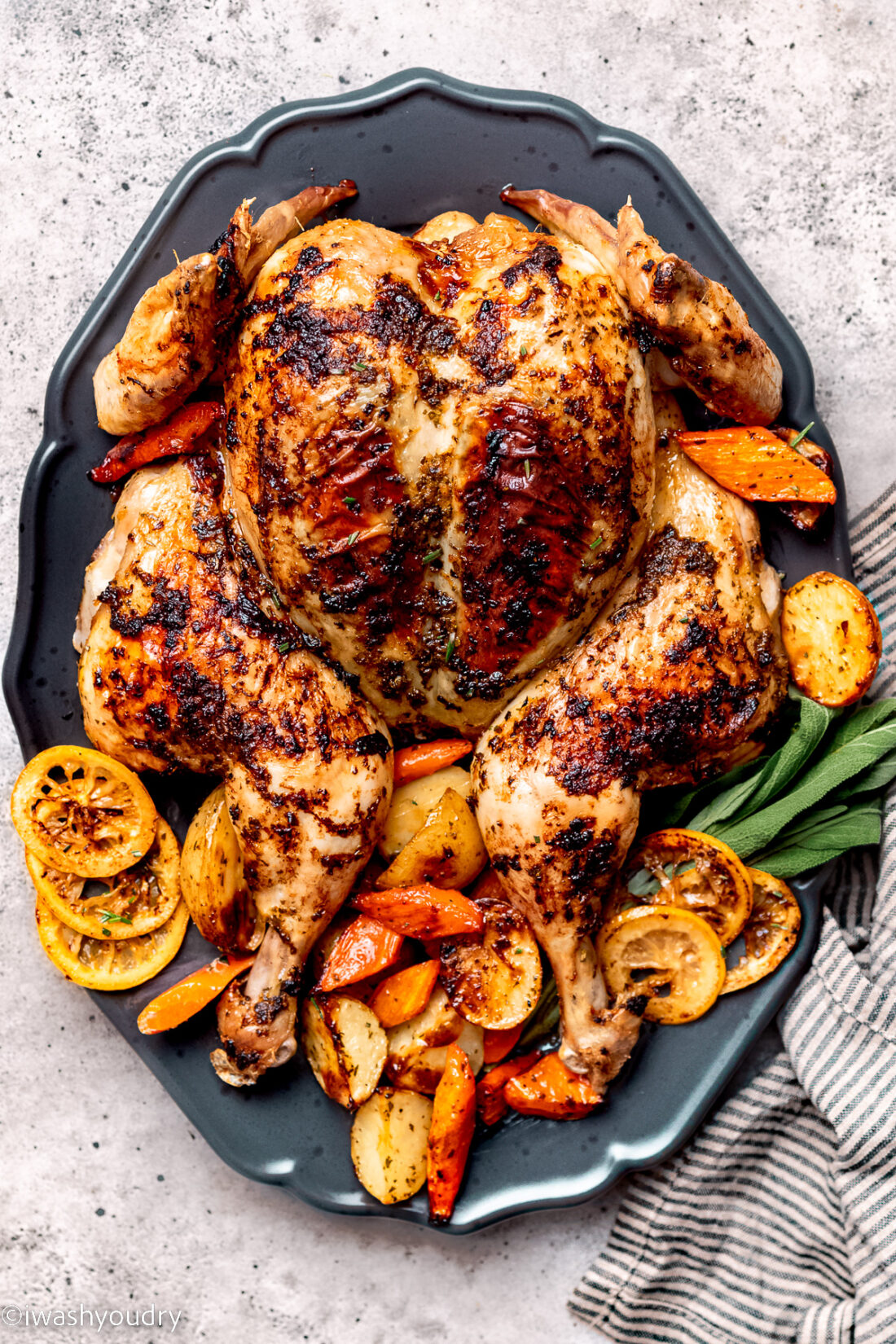 Whole roasted spatchcock chicken on platter with vegetables.