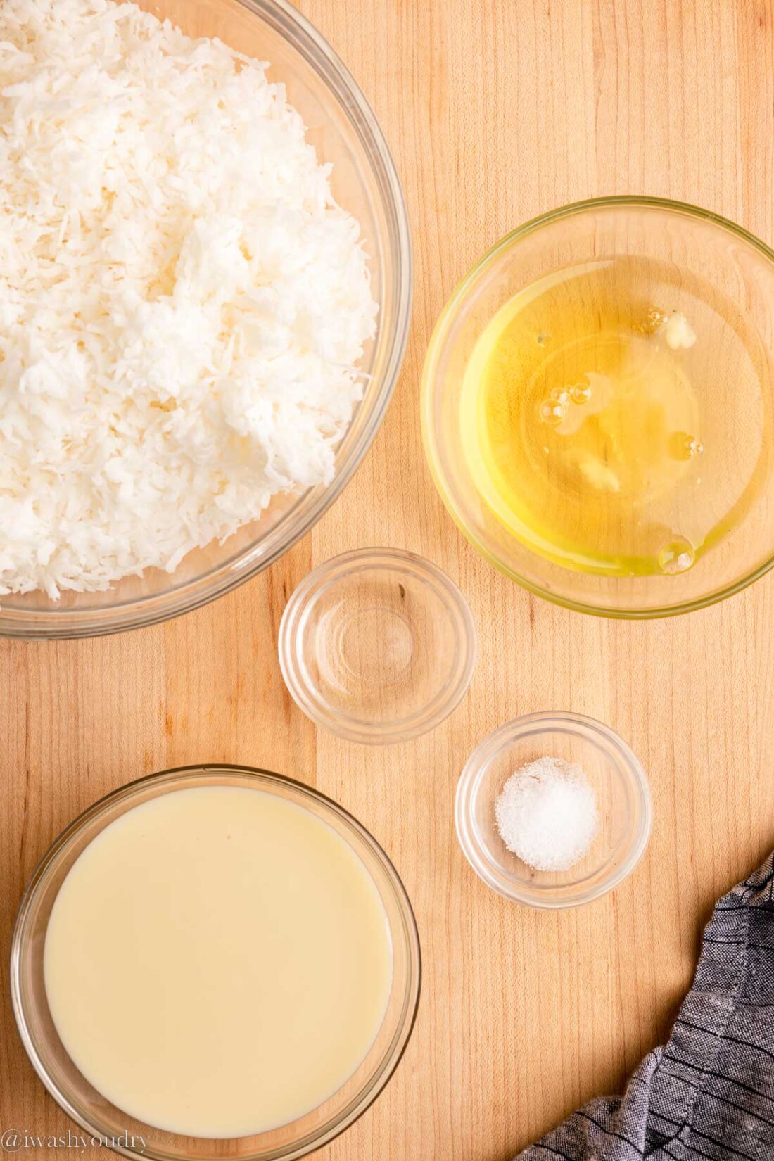 Ingredients for coconut macaroons on wood countertop in glass bowls. 