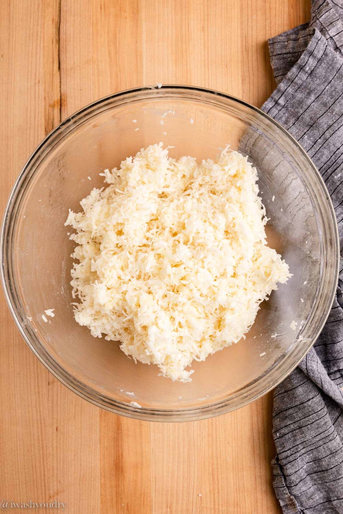 Coconut mixture in glass bowl near dish towel. 