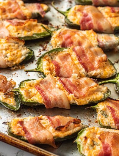 Cooked bacon wrapped Jalapeño Poppers on metal baking sheet.