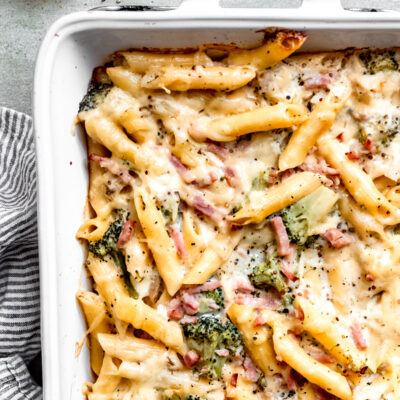 Baked chicken cordon bleu pasta in white pan on marble countertop.