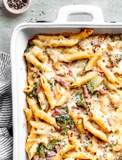 Baked chicken cordon bleu pasta in white pan on marble countertop.