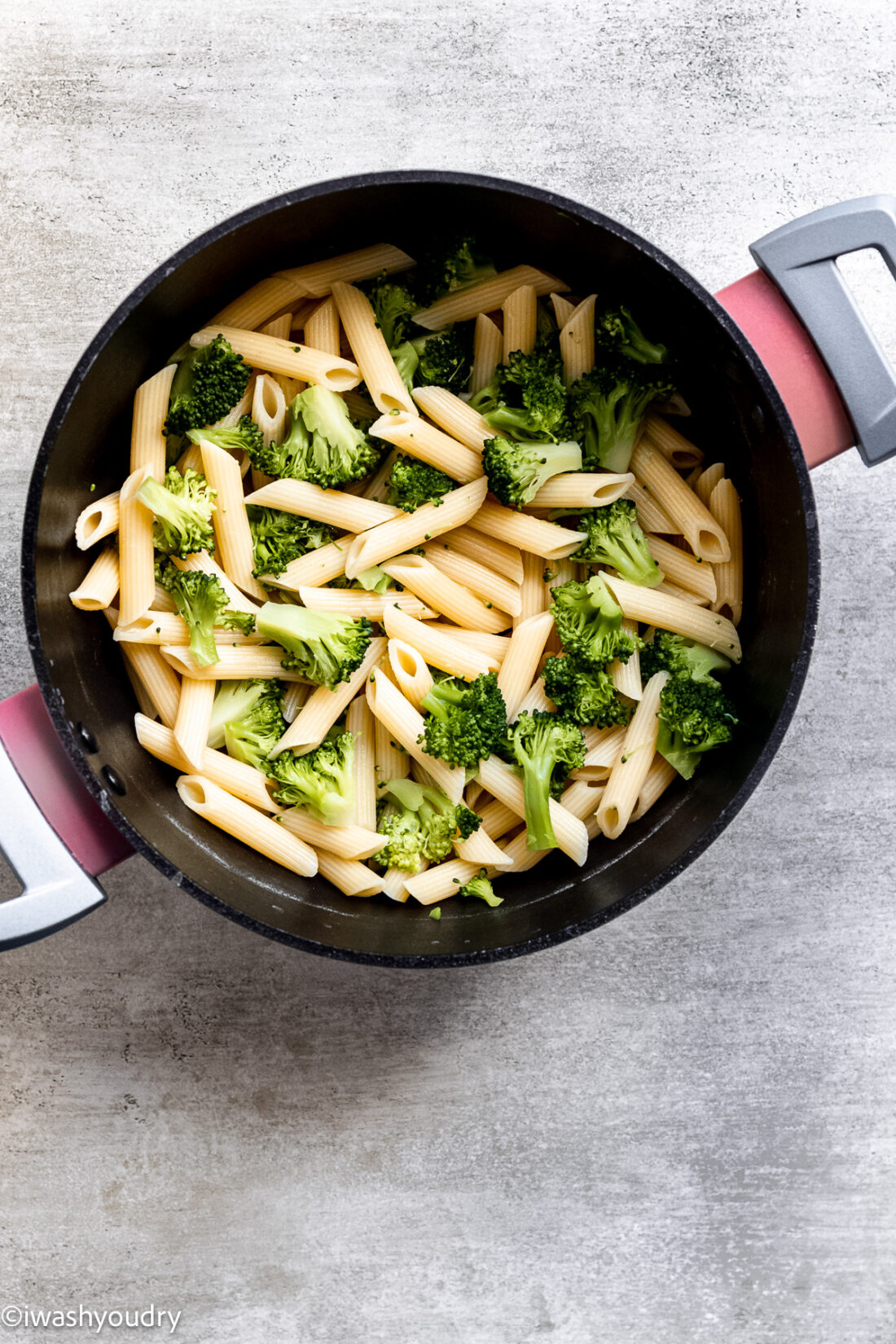 Cooked broccoli and penne in black pot. 