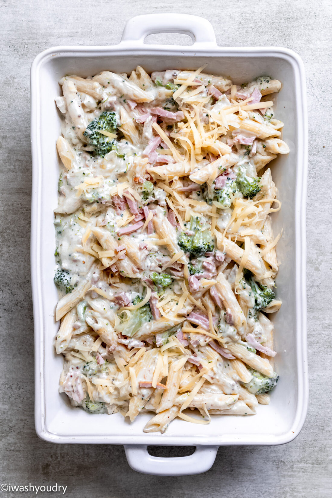 Unbaked chicken cordon bleu casserole in white baking dish. 