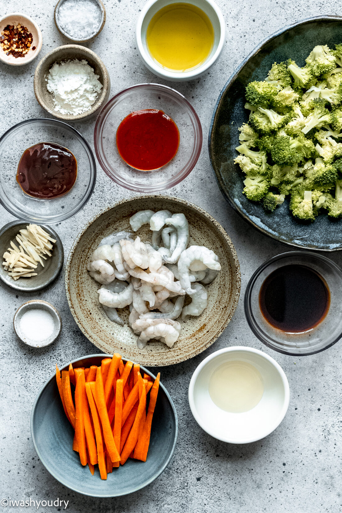 ingredients for shrimp stir fry on white surface with broccoli and carrots.