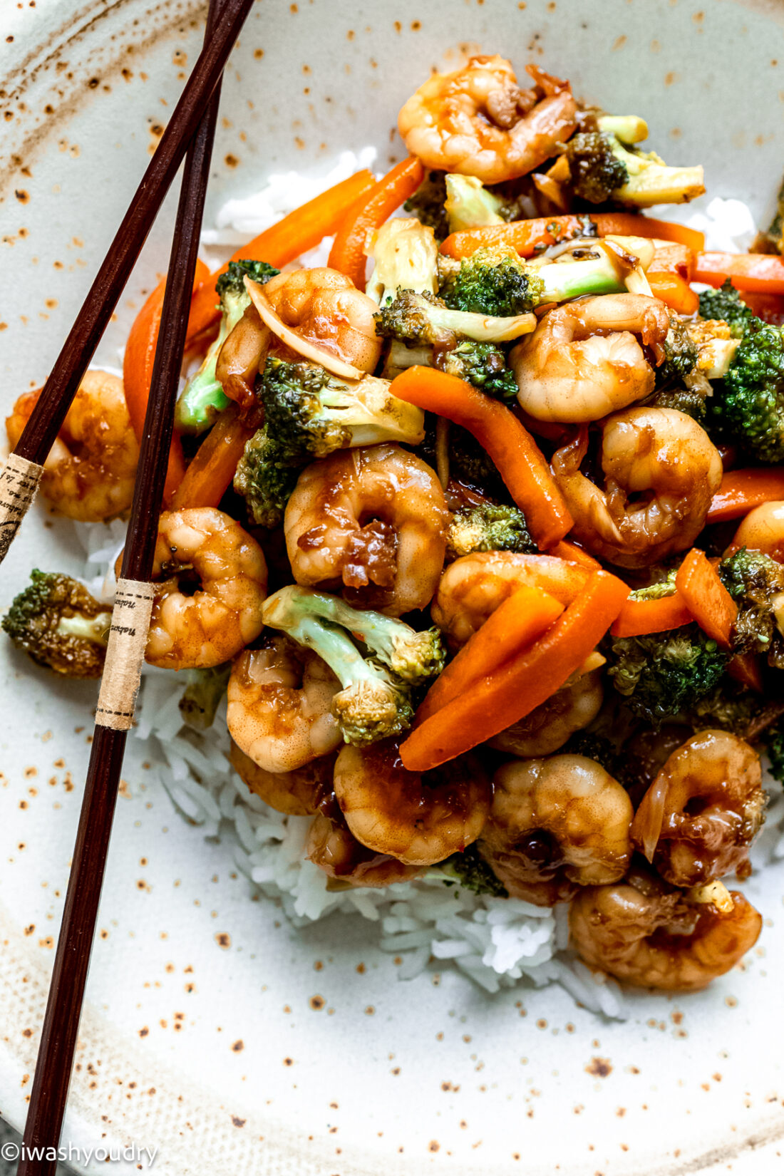 plate of shrimp with broccoli and carrots over white rice.