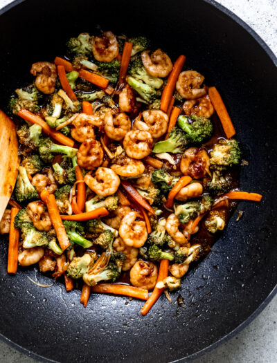 stir fry with broccoli and carrots in large black wok.