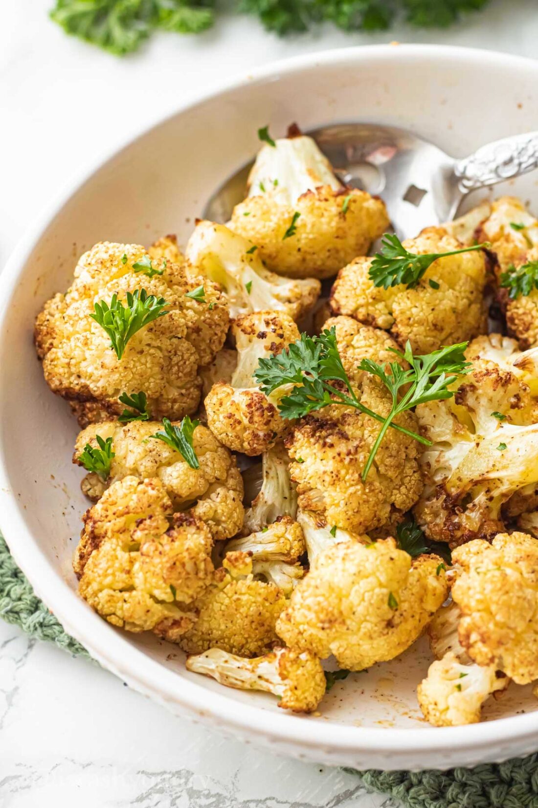 Cooked air fry cauliflower in white bowl with spoon.