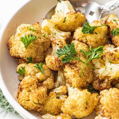 Cooked air fry cauliflower in white bowl with spoon.