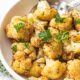 Cooked air fry cauliflower in white bowl with spoon.