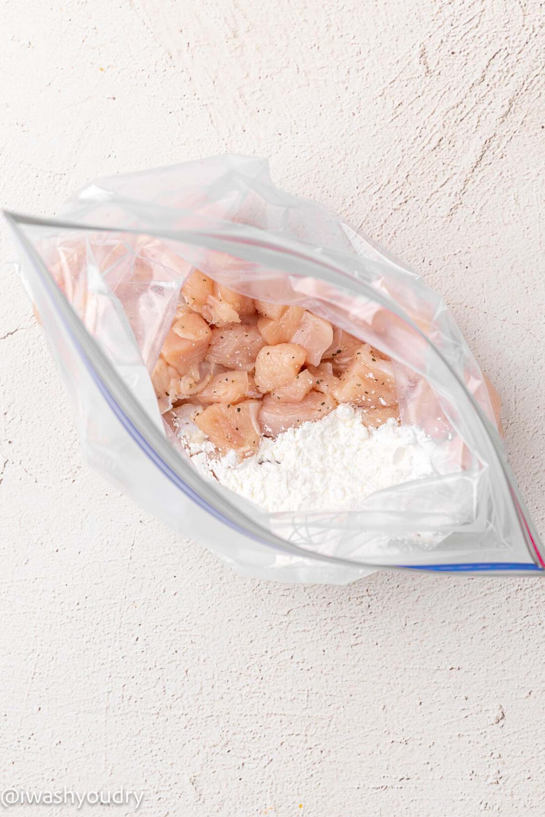 Raw seasoned chicken pieces in plastic bag with cornstarch. 