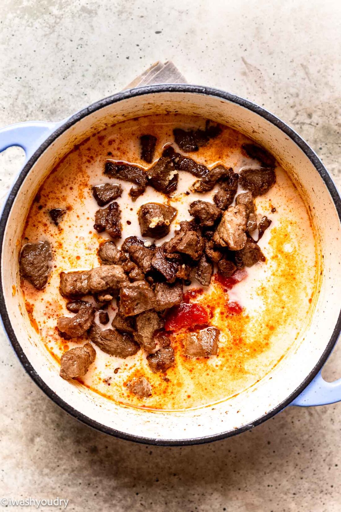 Liquid ingredients and beef in ceramic pot. 