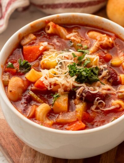 white bowl filled with minestrone soup and beans with parmesan cheese on top.