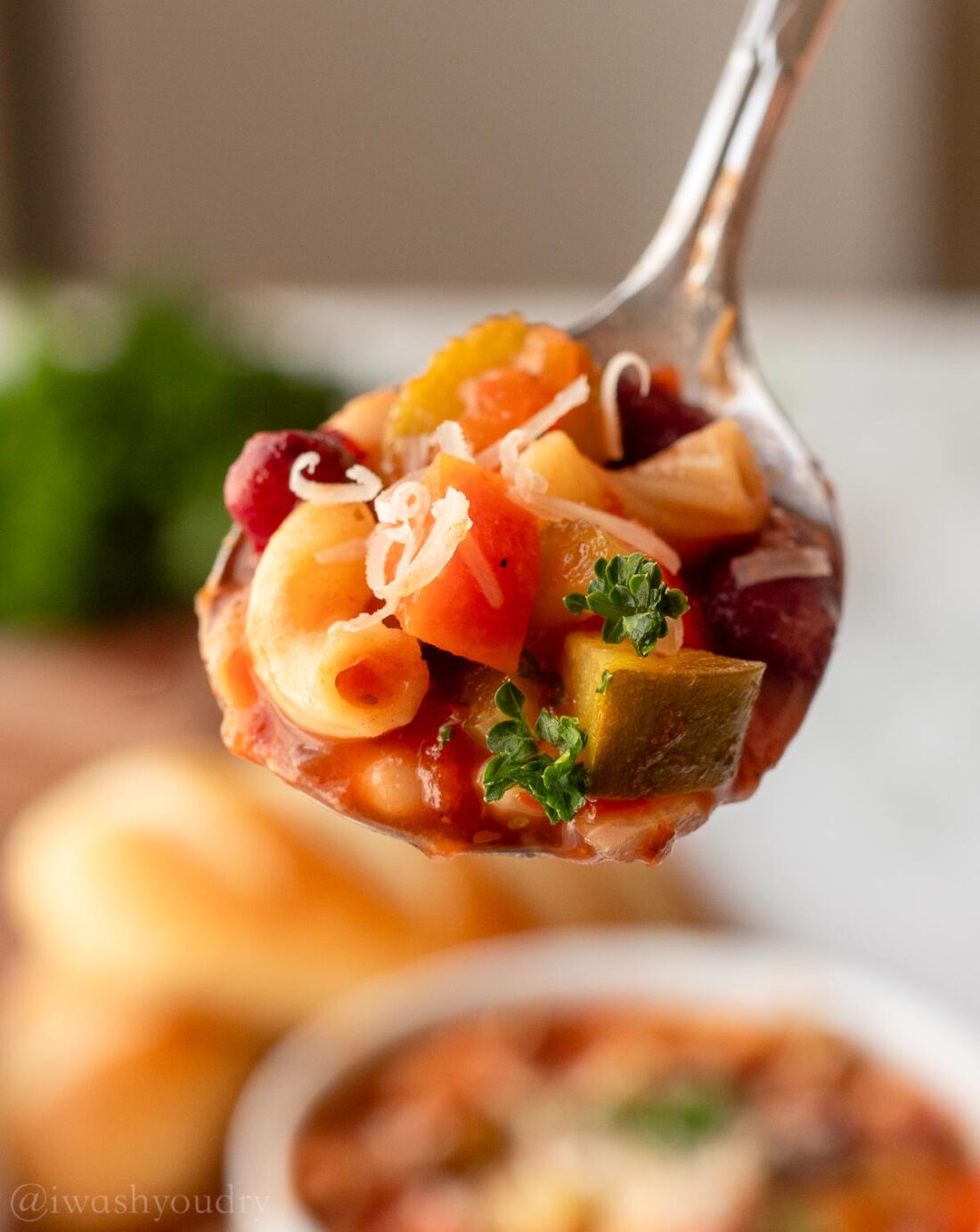 spoonful of minestrone soup with pasta and parmesan cheese.