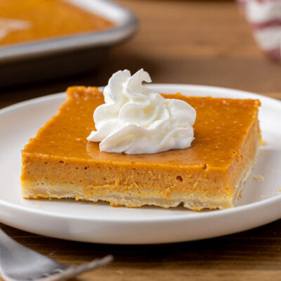 Slice of pumpkin pie bar on a white plate with a fork.