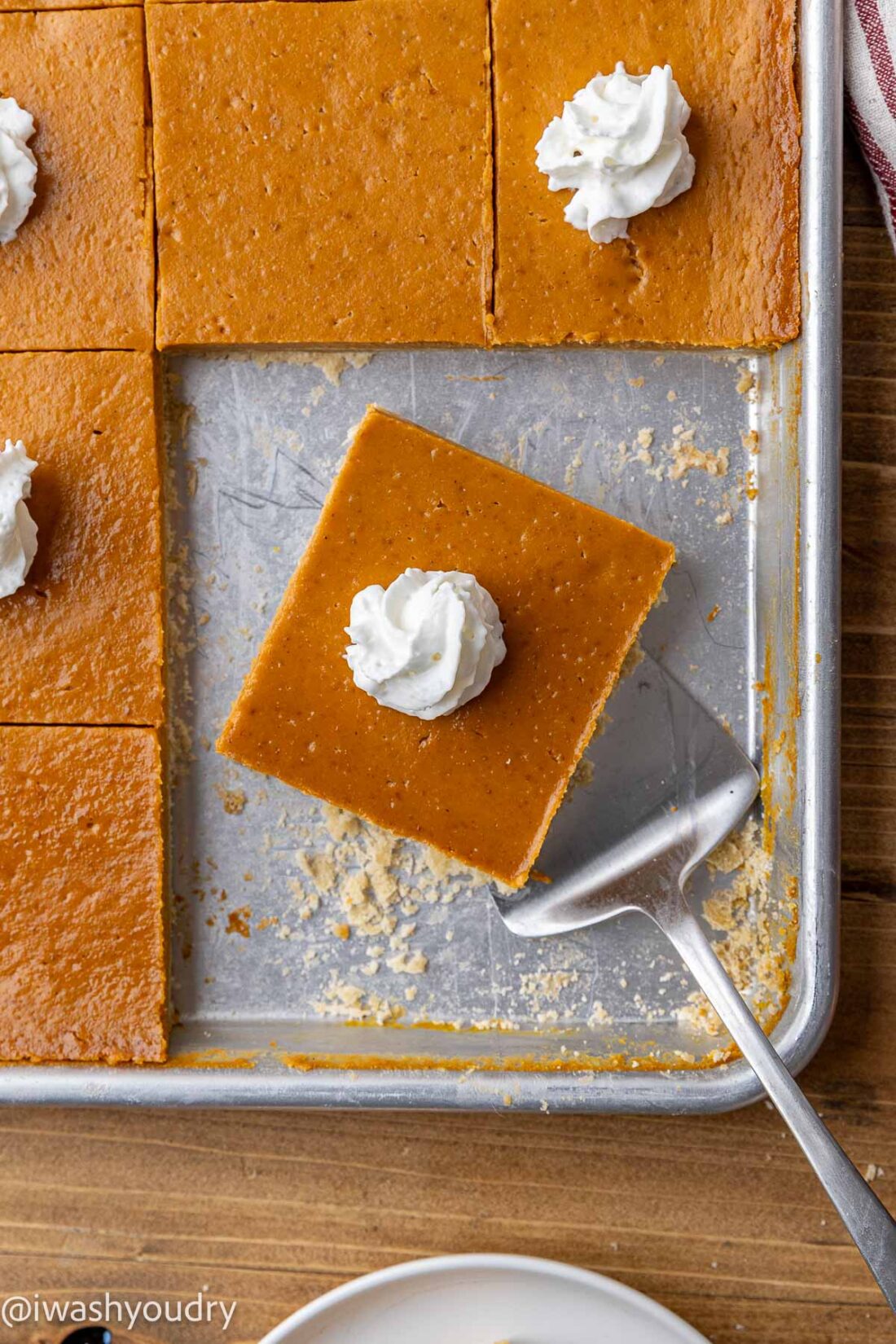 Slice of pumpkin pie bar on a spatula in a metal pan. 