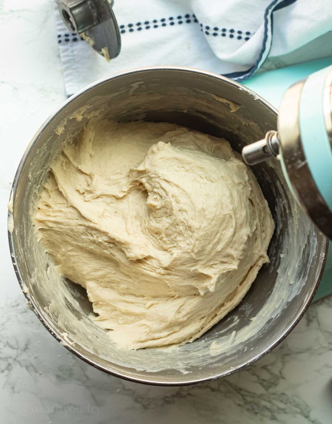 Raw kneaded roll dough in metal mixing bowl. 