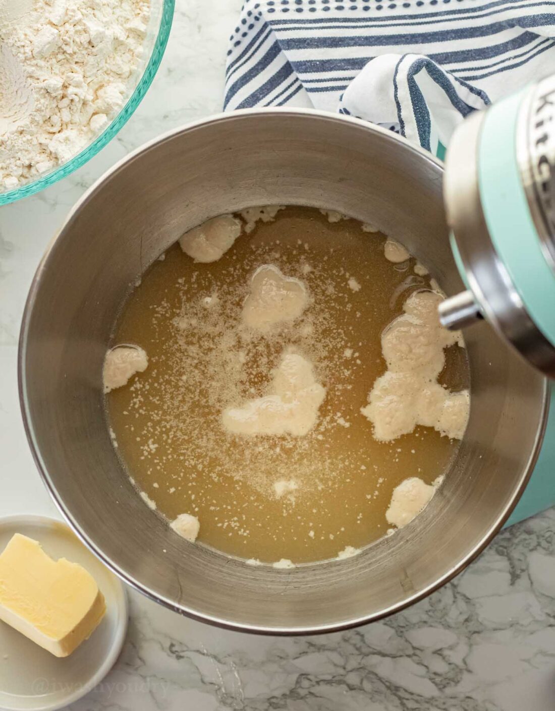 Metal mixing bowl with water and yeast inside. 