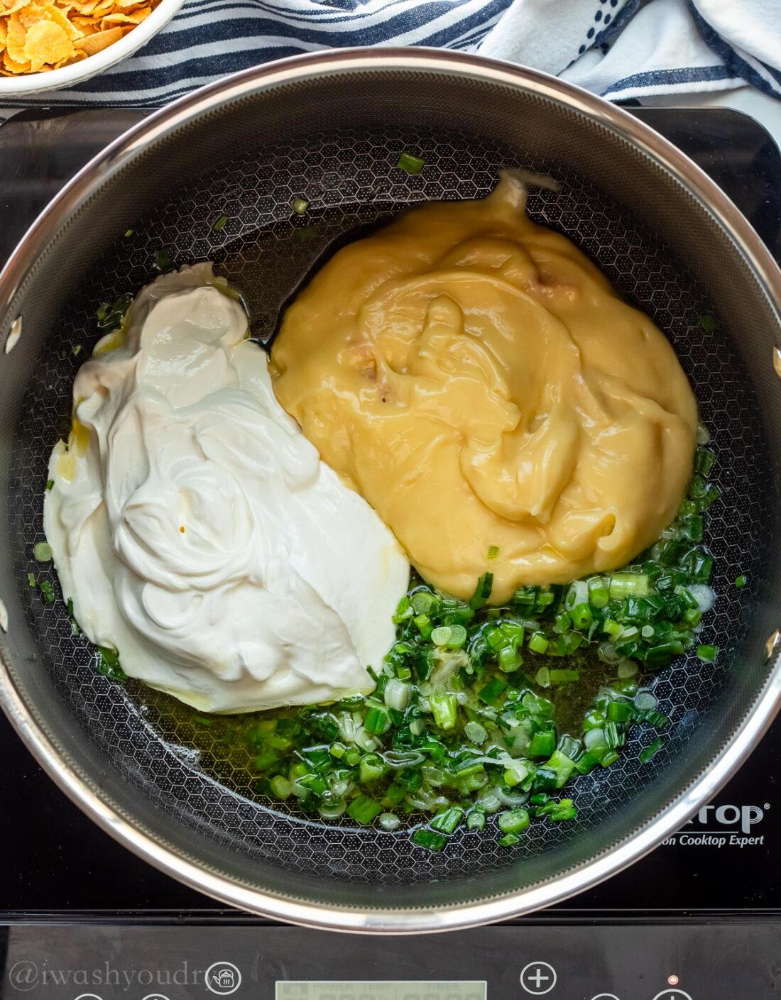 cream of chicken soup with sour cream and green onions in black pan.