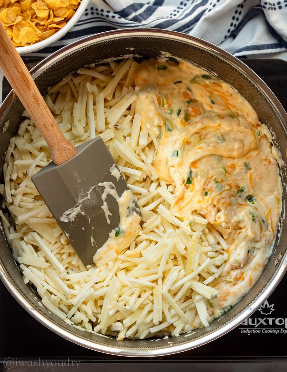 cheesy sauce with hashbrown potatoes in pan with spoon.