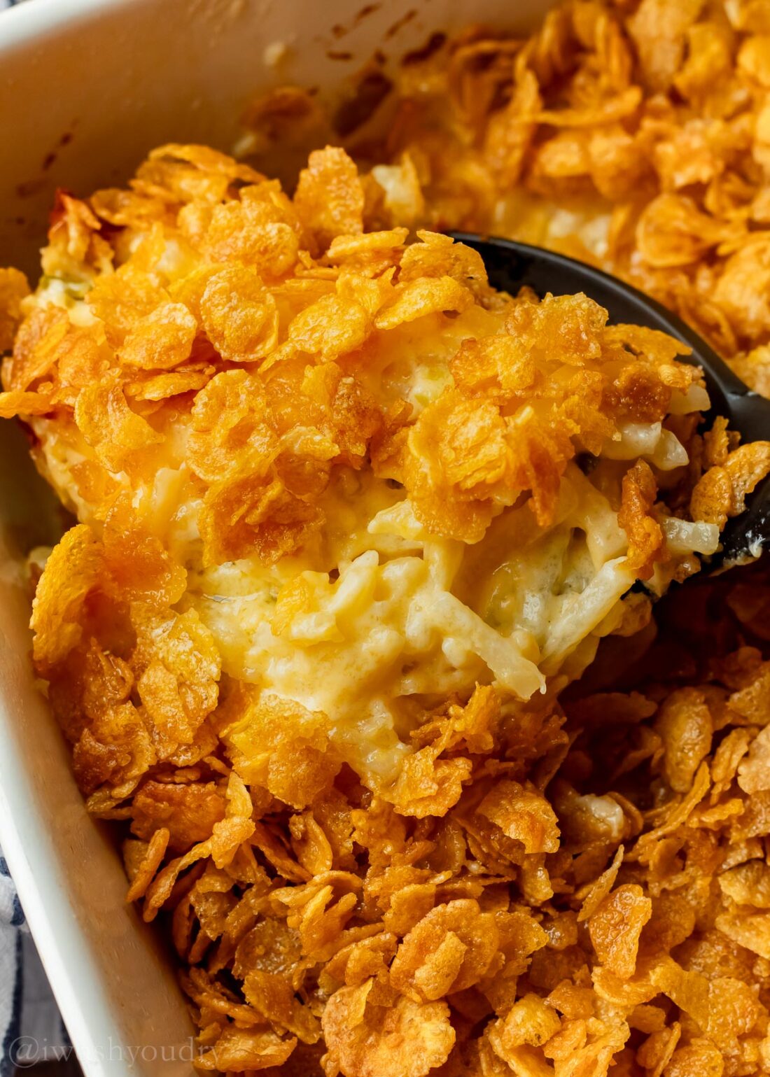 cheesy potato casserole with spoon filled dish.