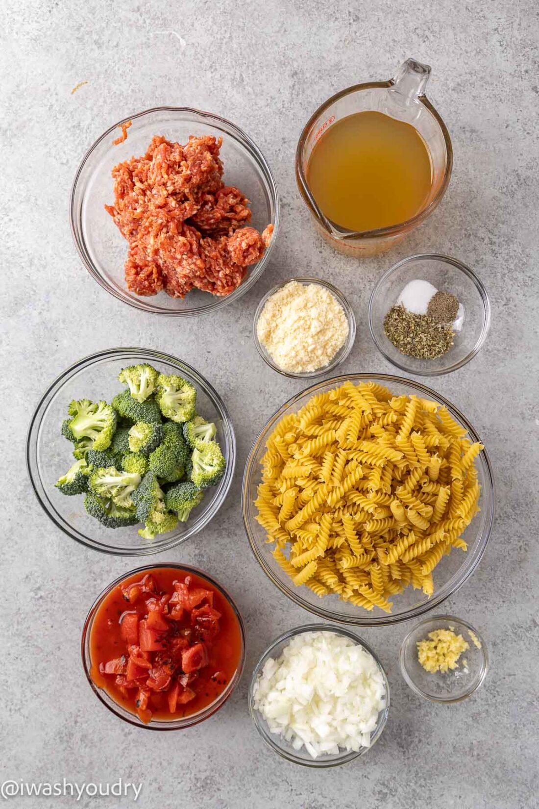 Ingredients for One Pot Sausage Pasta in glass bowls on marble countertop. 